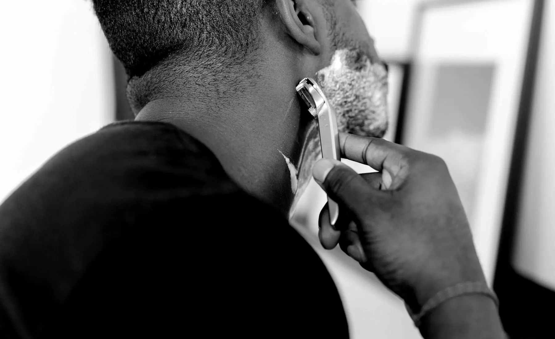 A man with shaving foam on his jaw, hand at his face