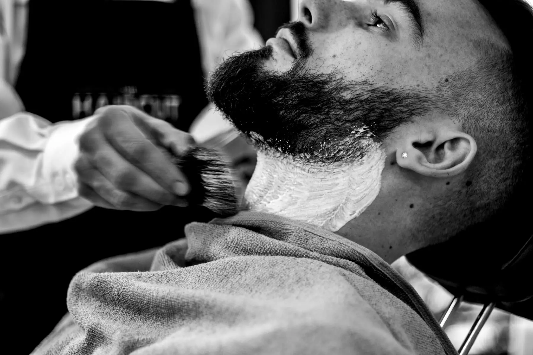 A beard being trimmed, close on the jawline and hands