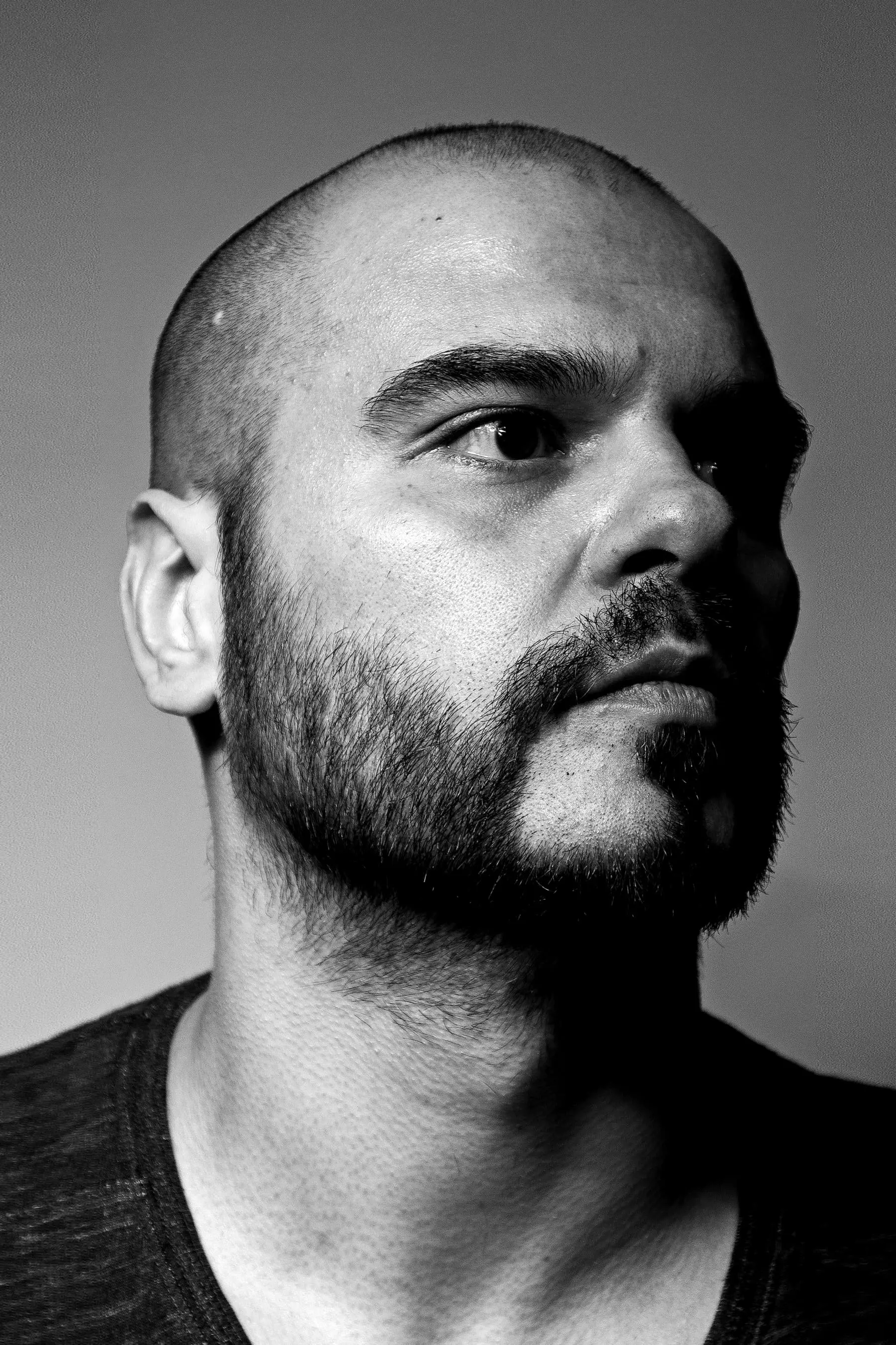 Nico — Portrait of a bald man with a full groomed beard looking off to the side