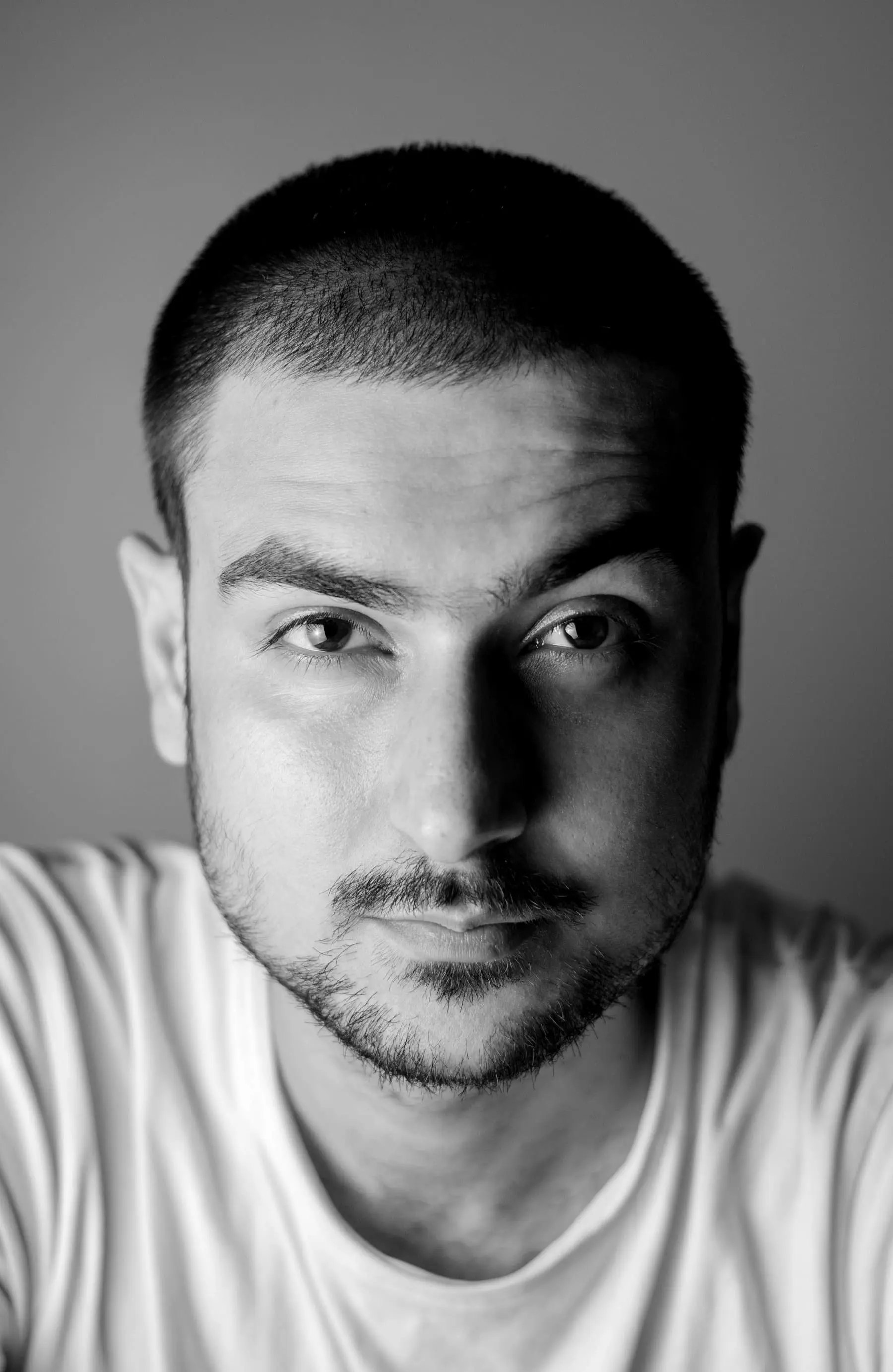 Front portrait of a man with a buzzed crop and light stubble