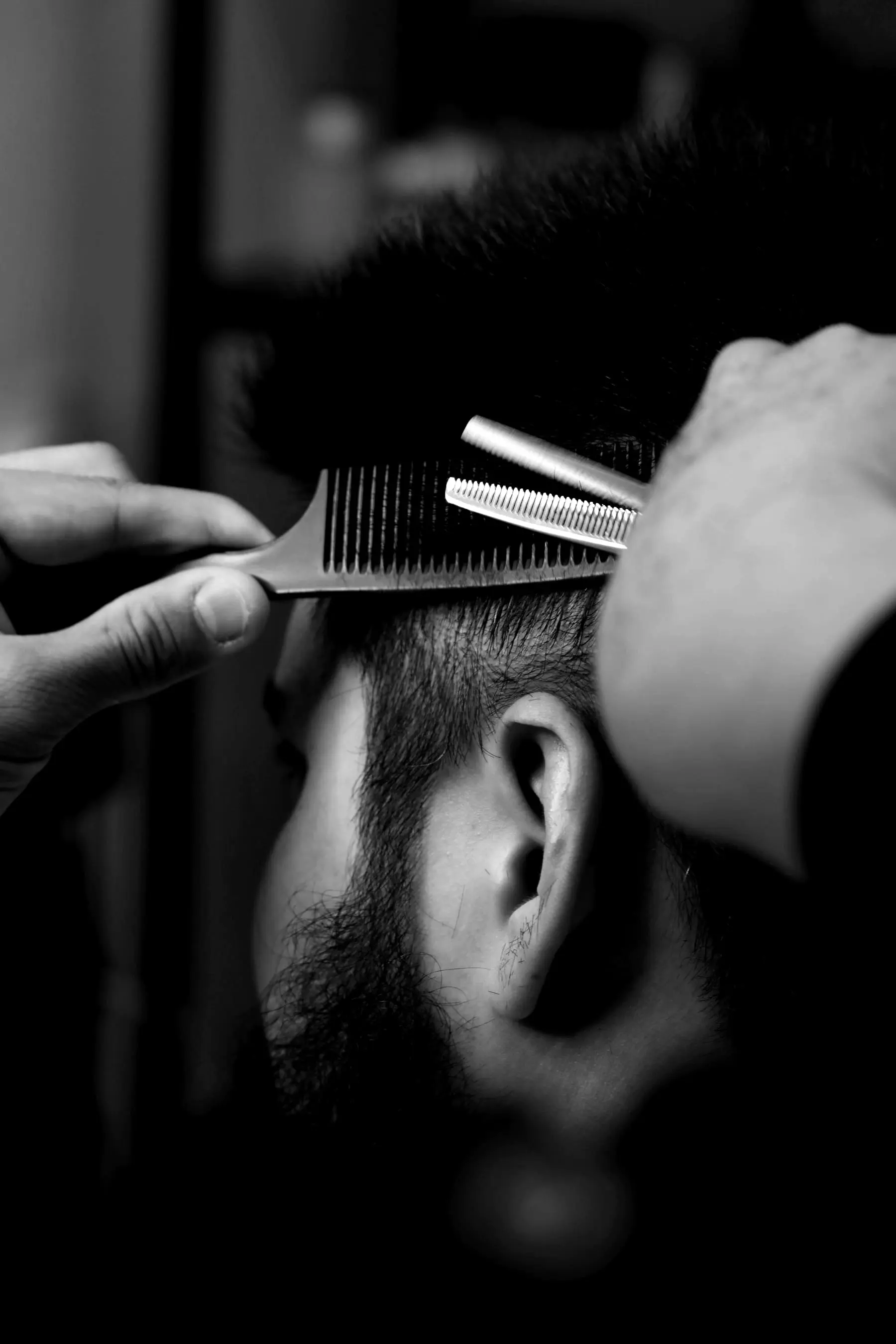 A barber thinning the back of a client's hair with shears and a comb