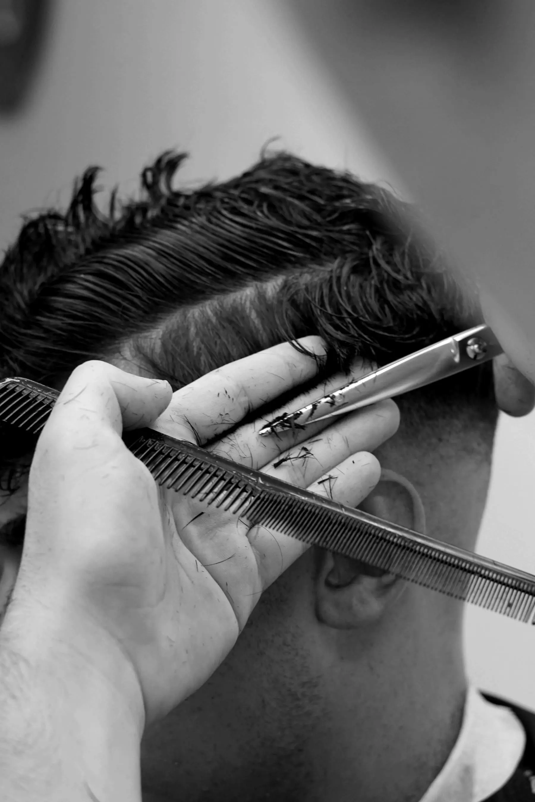 Close crop of a comb and scissors working over a short faded side