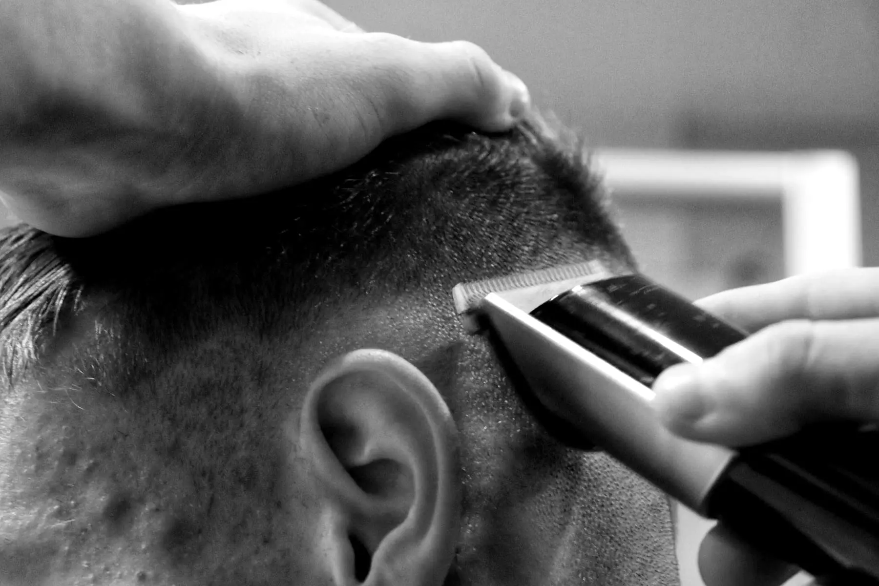 A clipper working around the ear on a fade