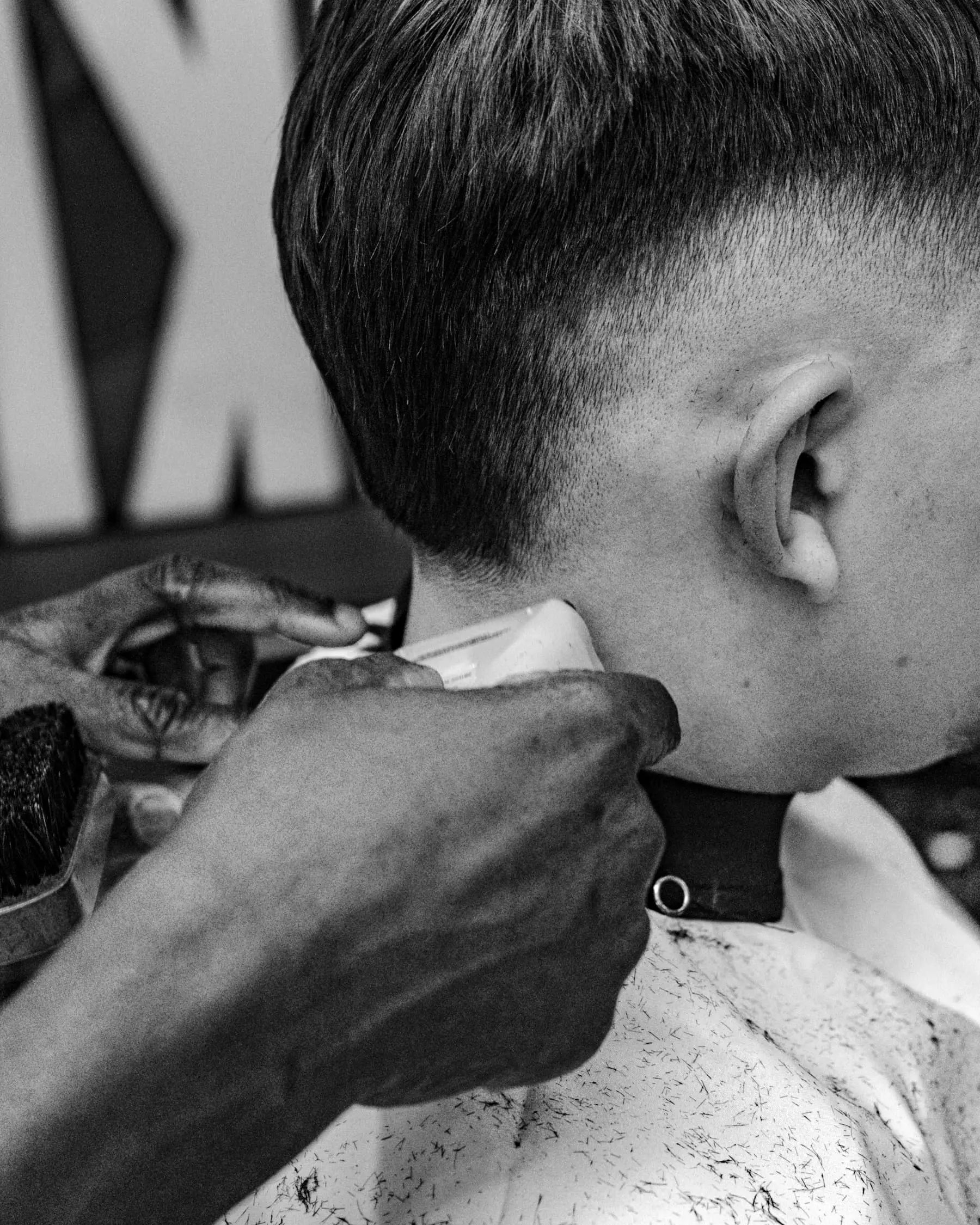 A barber tapering the nape of a client's neck with a trimmer