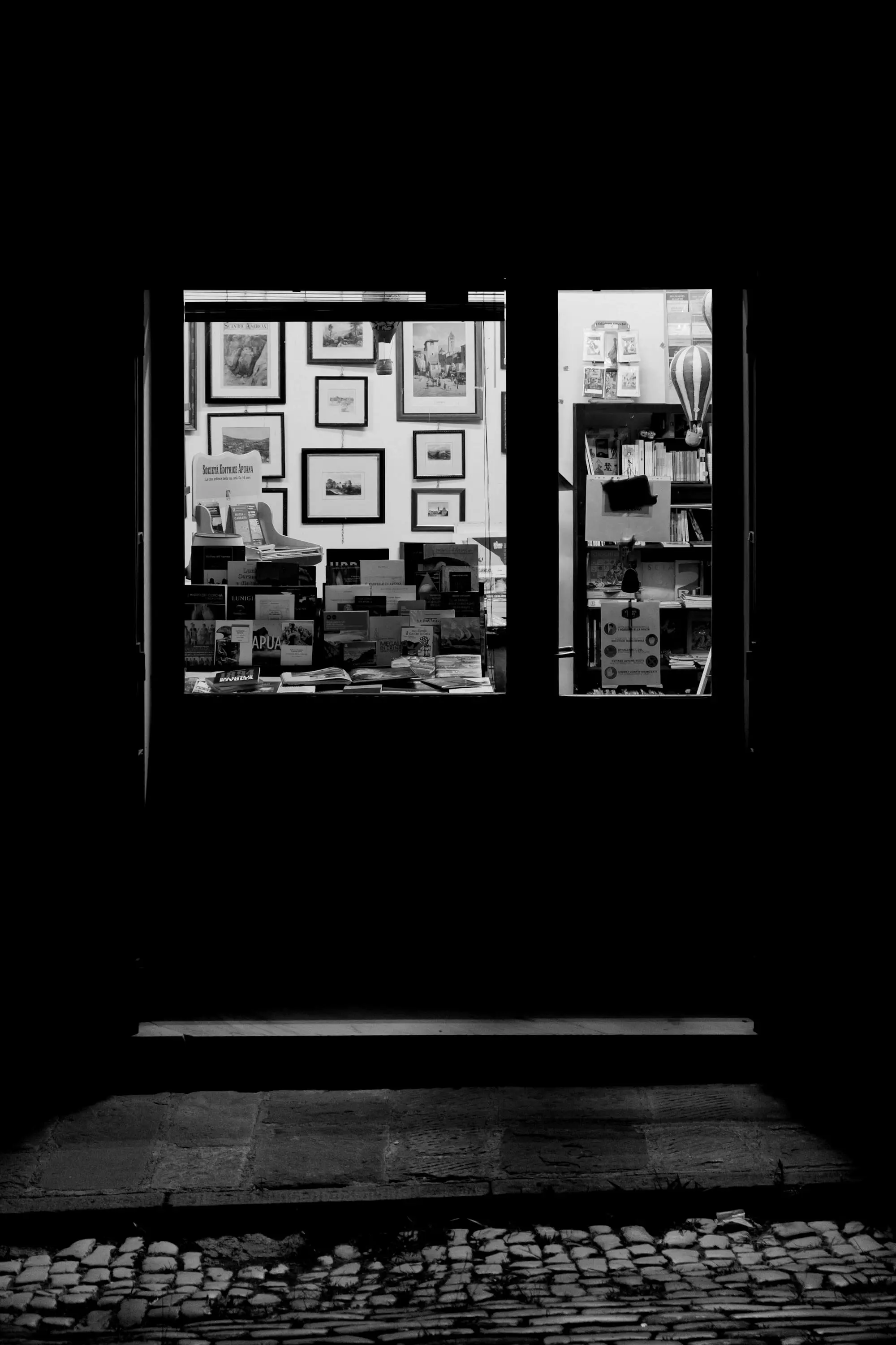 A shop door glowing with warm light in a dark street at night