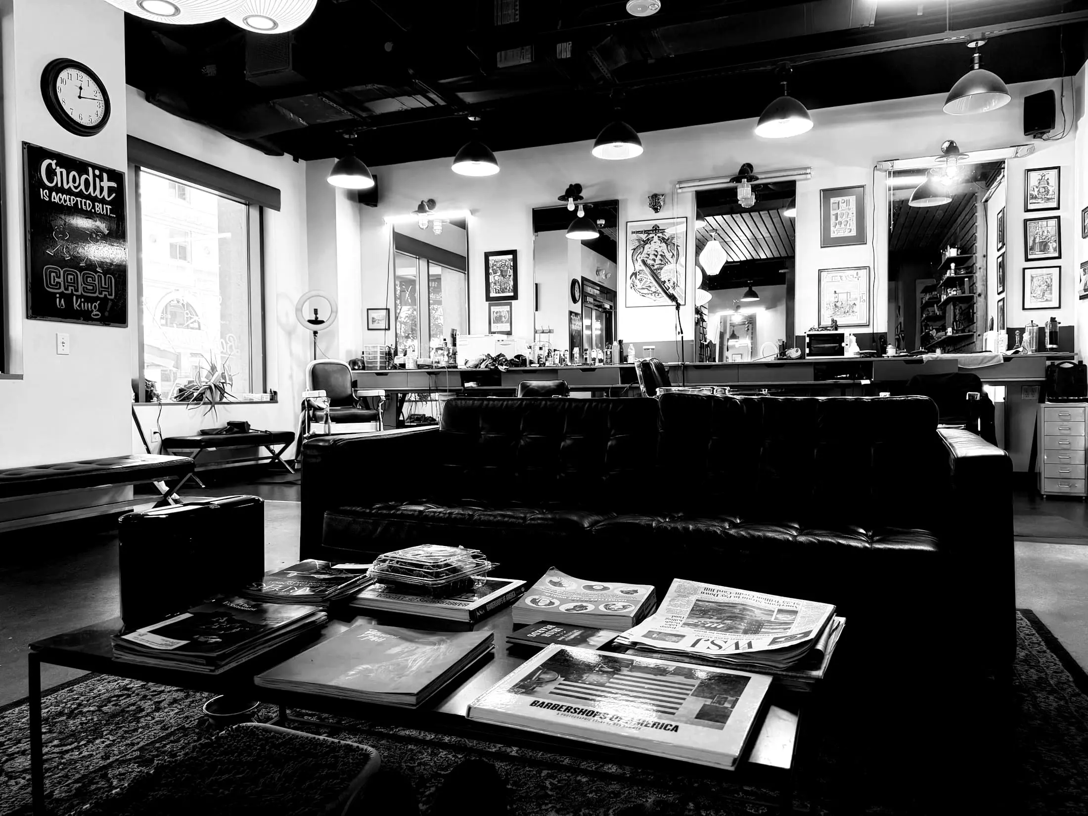 A barbershop waiting area with a couch and magazines on a table