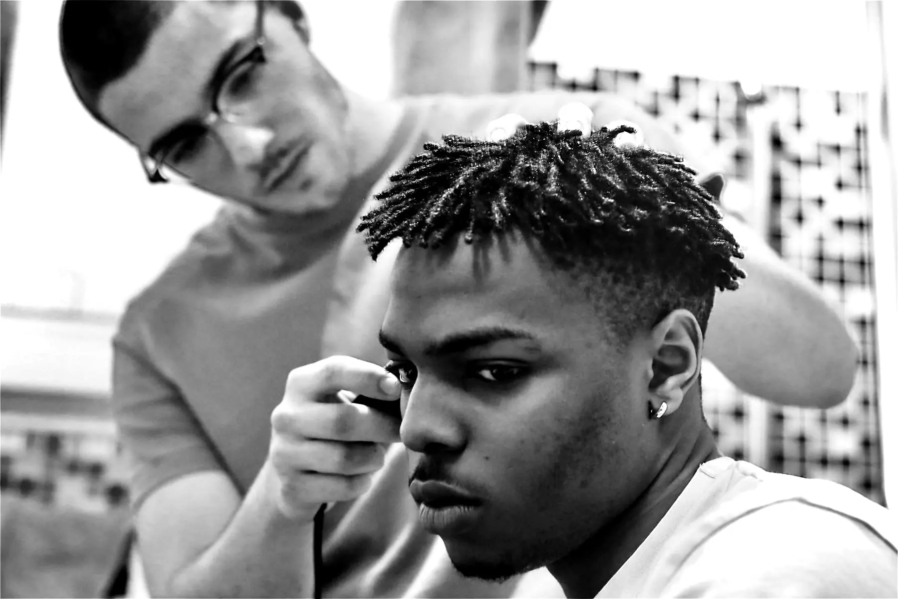 A barber tidying a curly textured top on a client