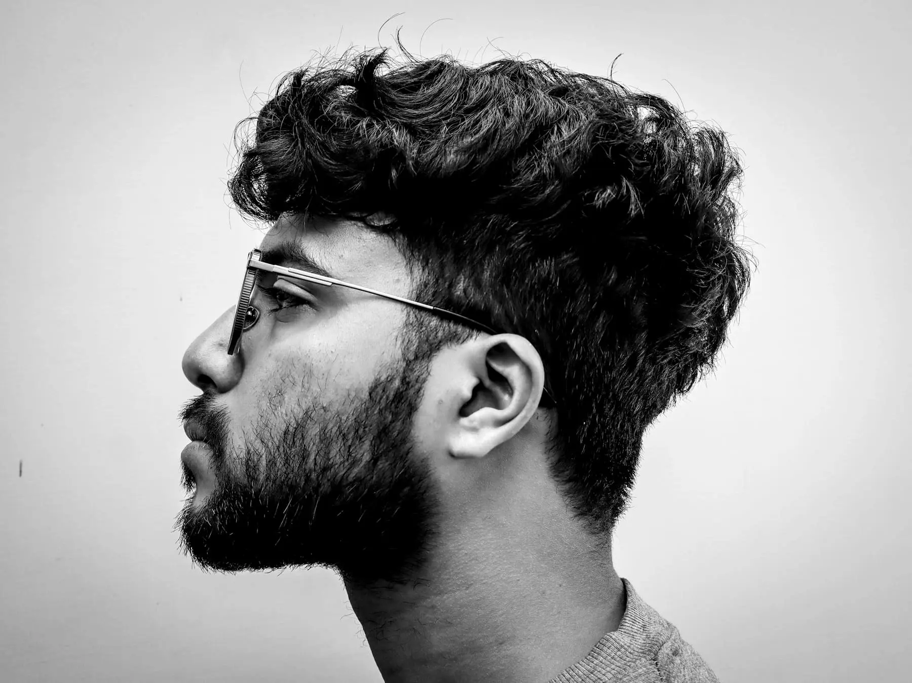 Profile of a bearded man in glasses with a curly textured top
